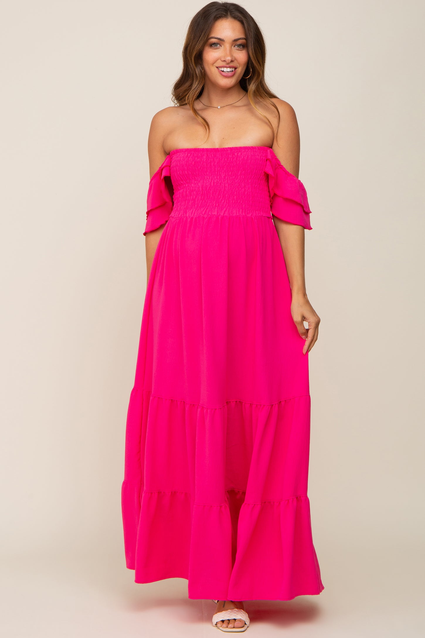woman wearing a hot pink off-the-shoulder smocked maternity maxi dress with tiered skirt