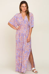 woman wearing a purple and orange floral print maxi dress with a smocked waist and side slit