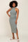 woman wearing a fitted sage green midi dress with a high neckline and side slit, paired with white slide sandals
