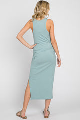 woman wearing a light green sleeveless maxi dress with a side slit and gathered detail on the back