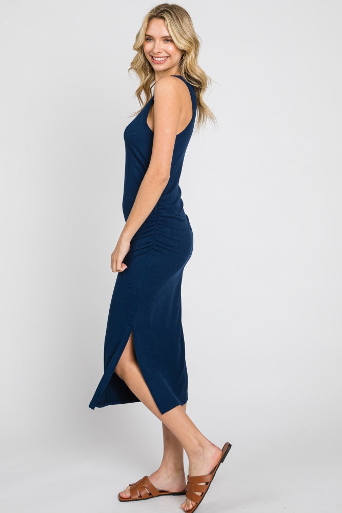 woman wearing a navy blue sleeveless midi dress with side ruching and a slit detail, styled with brown sandals