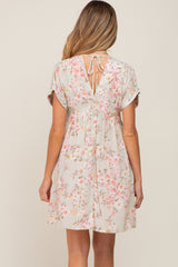 Back view of a woman wearing a light grey floral babydoll dress with a tie-back neckline and short sleeves