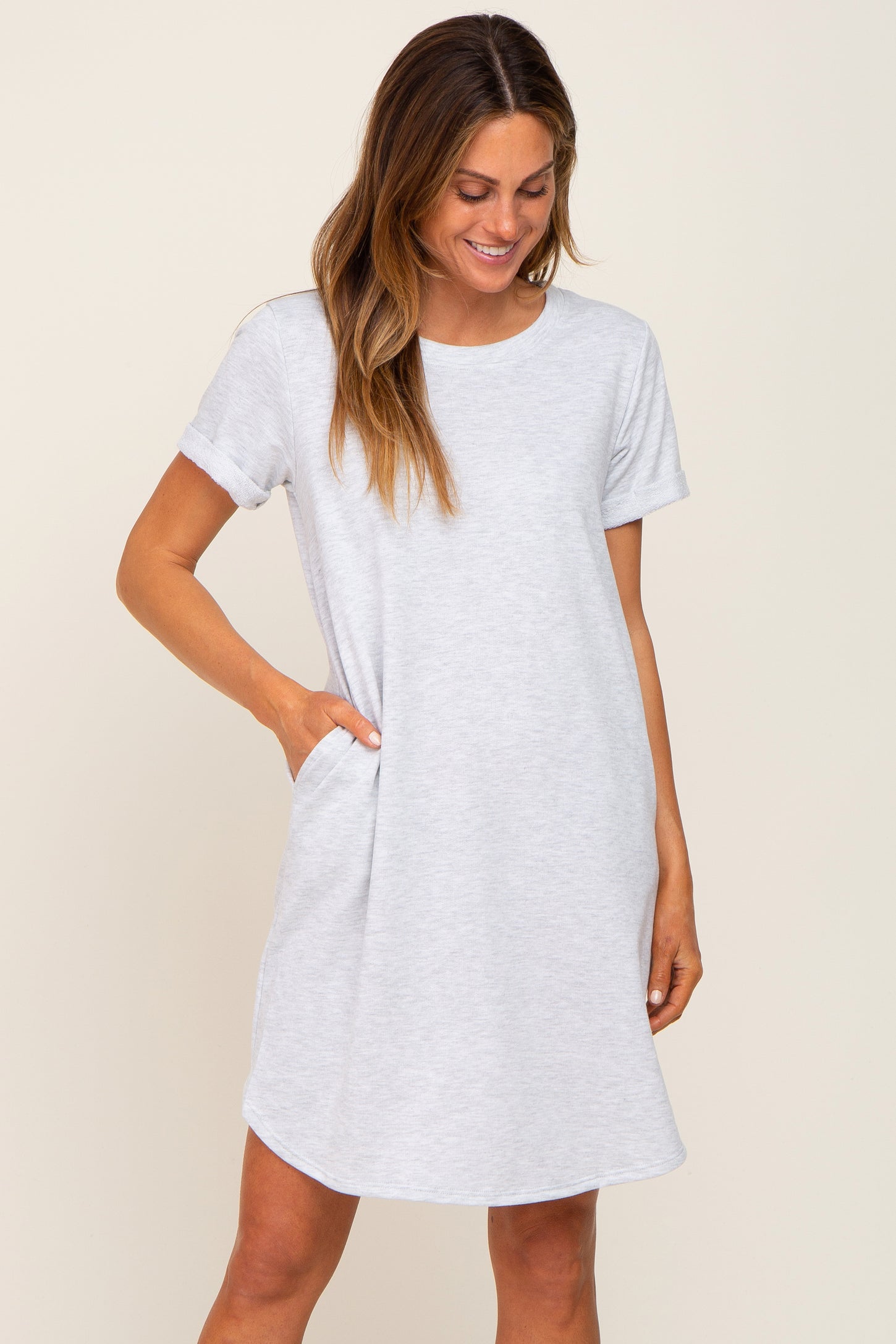 woman wearing a light gray short sleeve t-shirt dress with pockets and a relaxed fit