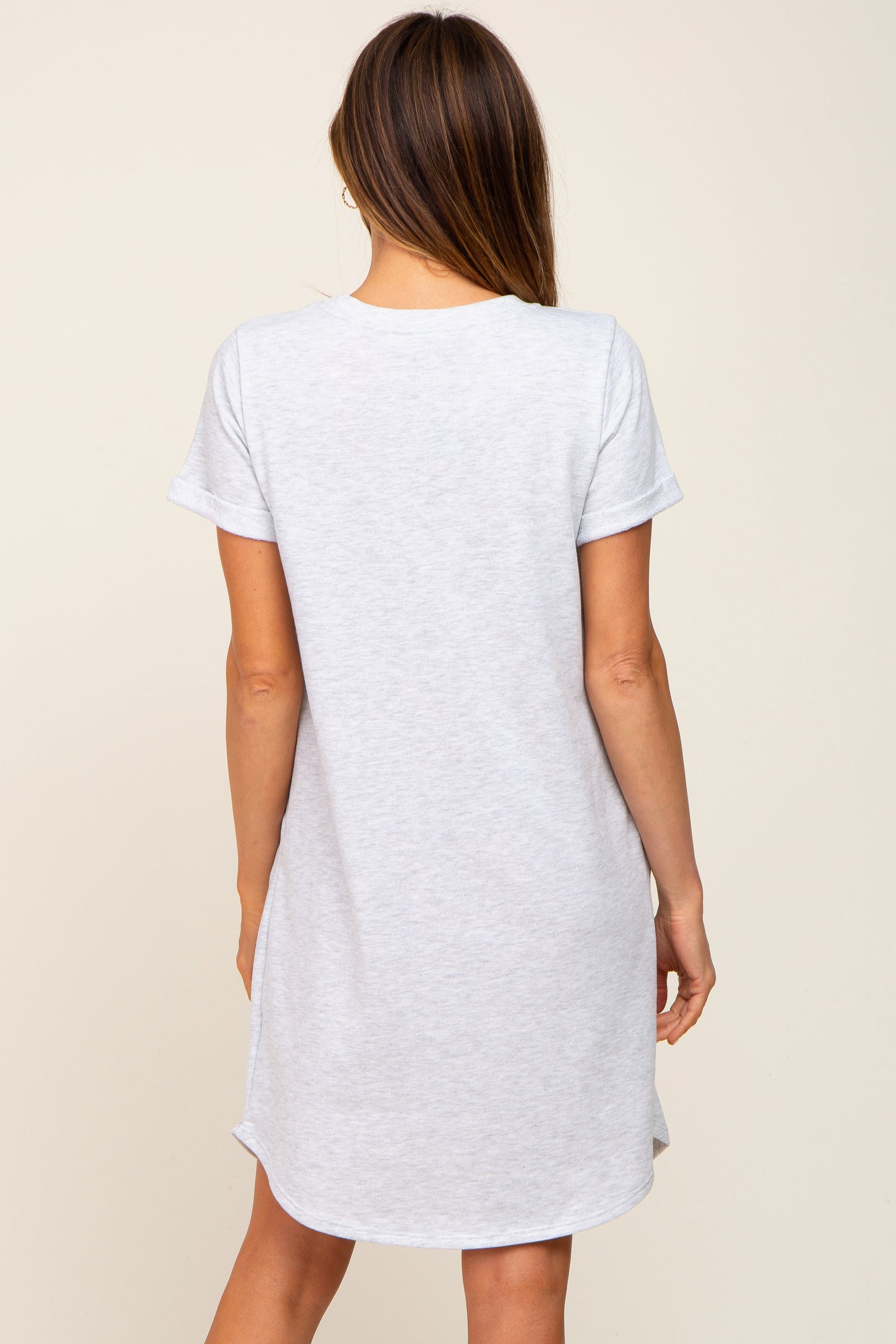 woman wearing a light gray short sleeve t-shirt dress with a curved hem and relaxed fit, shown from the back