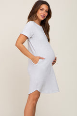 woman wearing a gray short sleeve maternity dress with side pockets and holding her baby bump