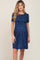 woman wearing a navy blue short sleeve maternity dress with white floral print and a gathered waist, showing a baby bump