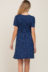 woman wearing a navy blue short sleeve maternity dress with a white floral print, showing the back view