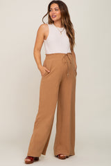 Pregnant woman wearing camel wide leg maternity pants and a white ribbed tank top