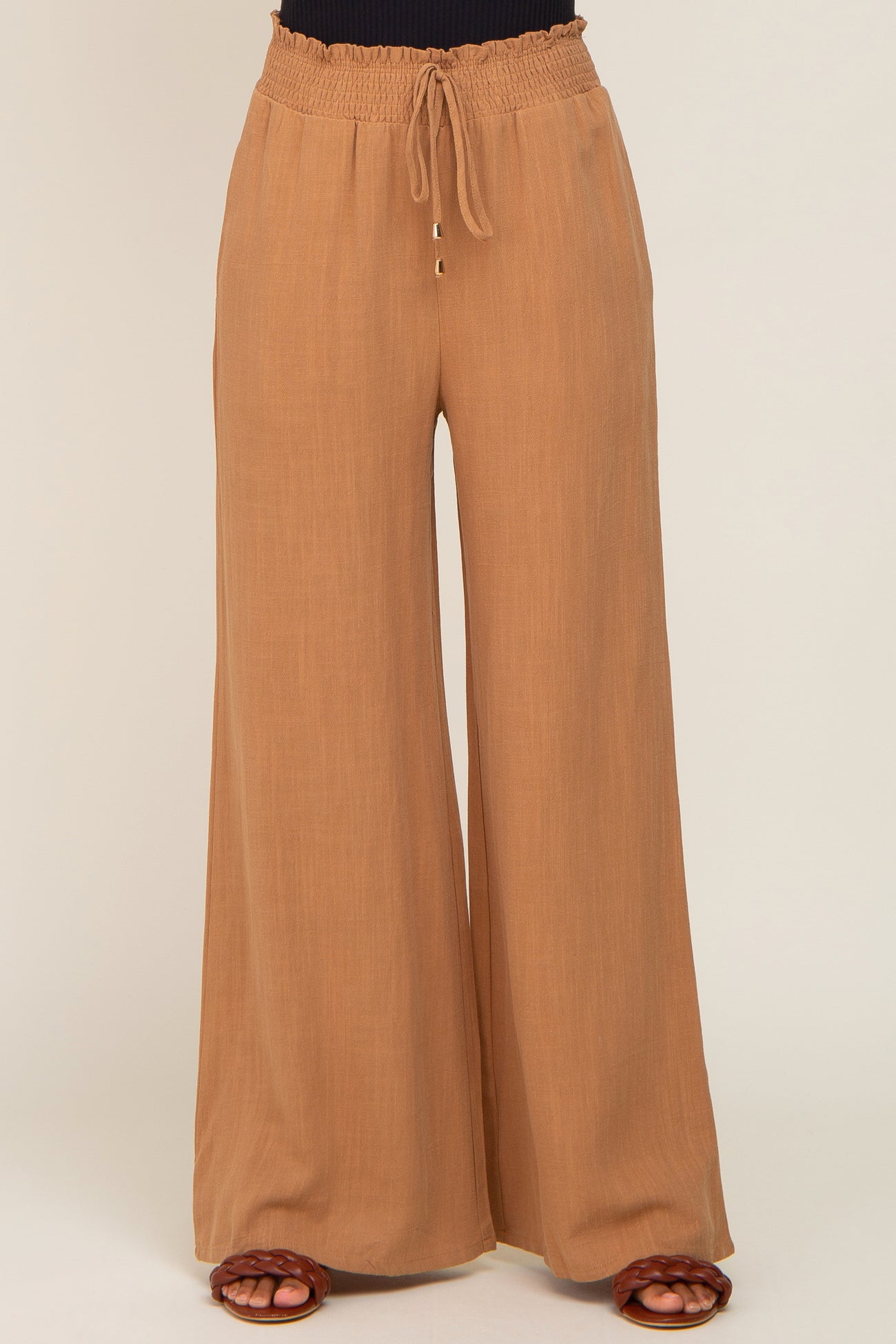 Tan wide-leg trousers with a smocked drawstring waistband and flowy fit