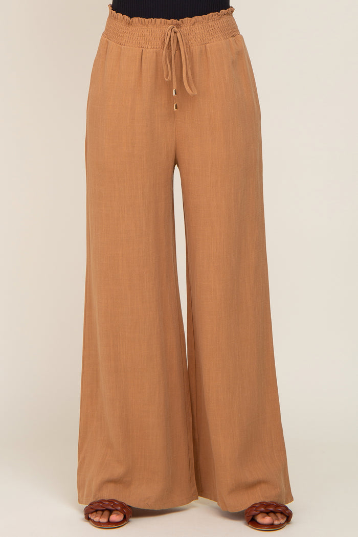 Tan wide-leg trousers with a smocked drawstring waistband and flowy fit