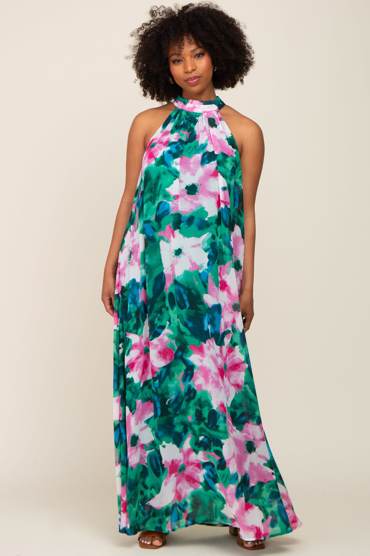 Woman wearing a pink and green floral print halter neck maternity maxi dress