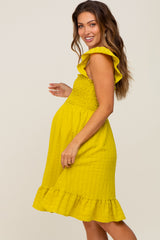 Smiling pregnant woman wearing a yellow smocked maternity dress with ruffle sleeves and hem
