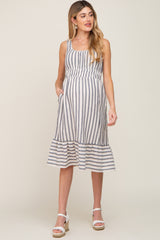 pregnant woman wearing a blue and white striped maternity midi dress with ruffle hem and white wedge sandals