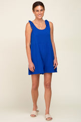 woman wearing a bright blue sleeveless dress with tie details on the straps and a flared skirt