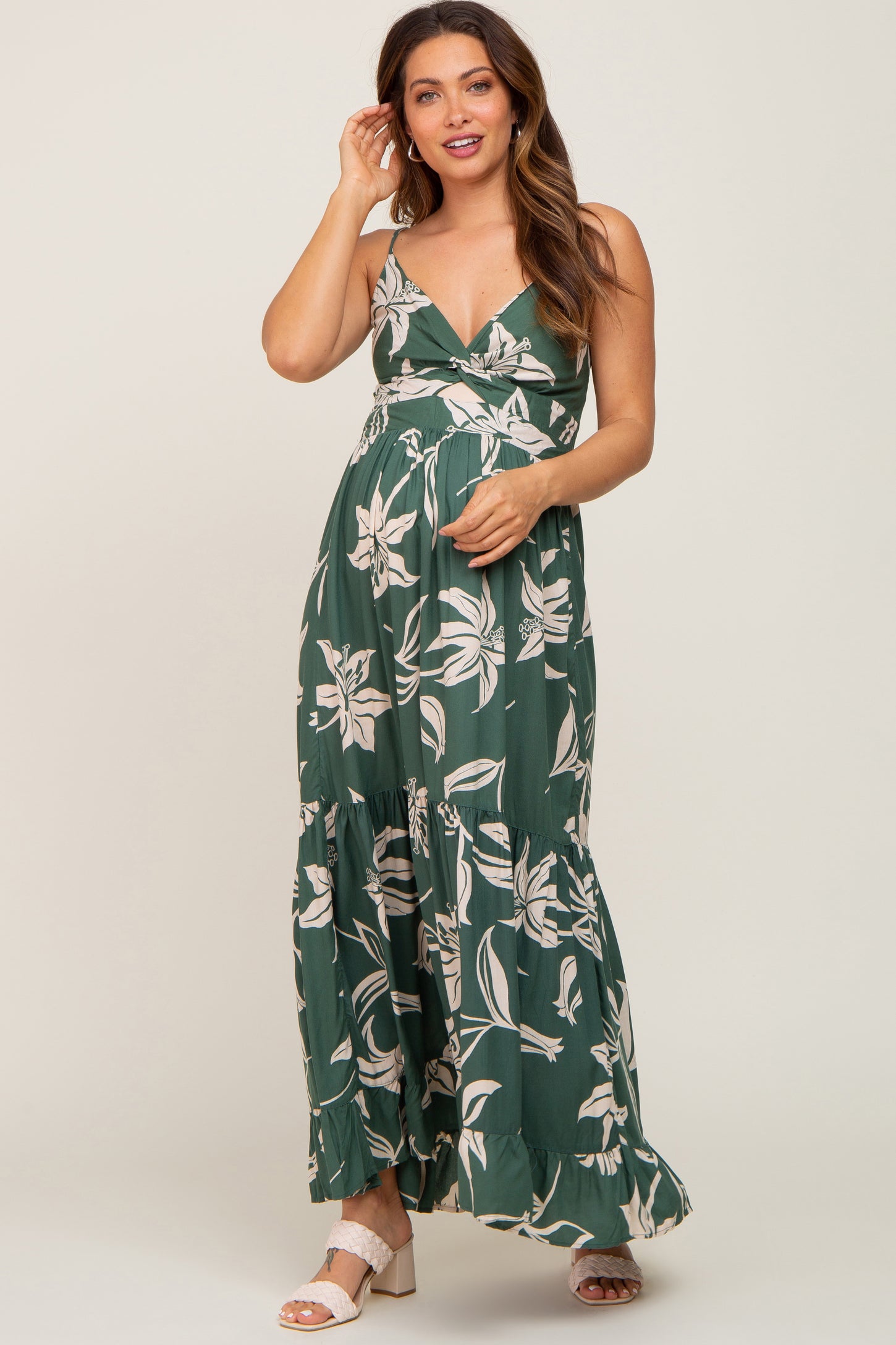 woman wearing a green floral maternity maxi dress with a twist front and tiered skirt