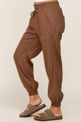 person wearing brown linen jogger pants with drawstring waist and elastic cuffs paired with olive green slide sandals
