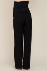 woman wearing black maternity pants with a ruched waistband, standing sideways to show the back view