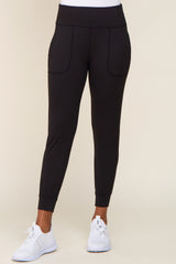 woman wearing black high-waisted joggers with front pockets and white athletic sneakers