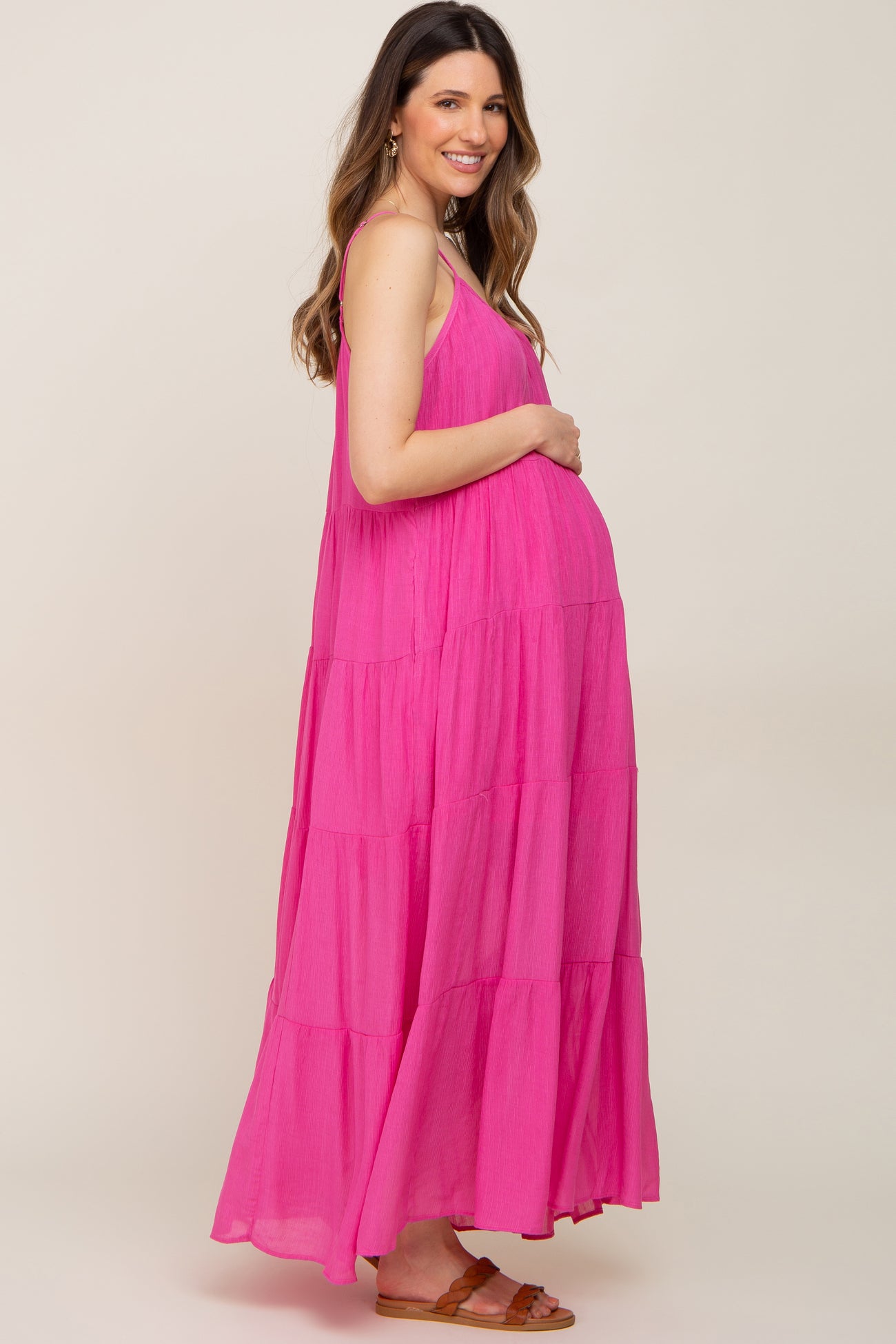 smiling pregnant woman wearing a bright pink tiered maternity maxi dress with spaghetti straps