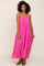 woman with curly hair wearing a hot pink tiered maxi dress with spaghetti straps and black sandals