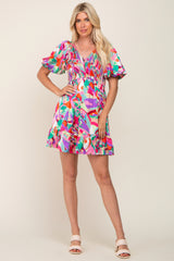 Woman wearing a colorful abstract print mini dress with puff sleeves and smocked bodice