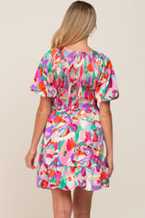Back view of a woman wearing a colorful abstract print mini dress with smocked bodice and puff sleeves