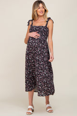 woman wearing a black floral maternity dress with ruffled straps and a visible baby bump