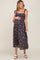 woman wearing a black floral maternity dress with ruffled straps and a visible baby bump