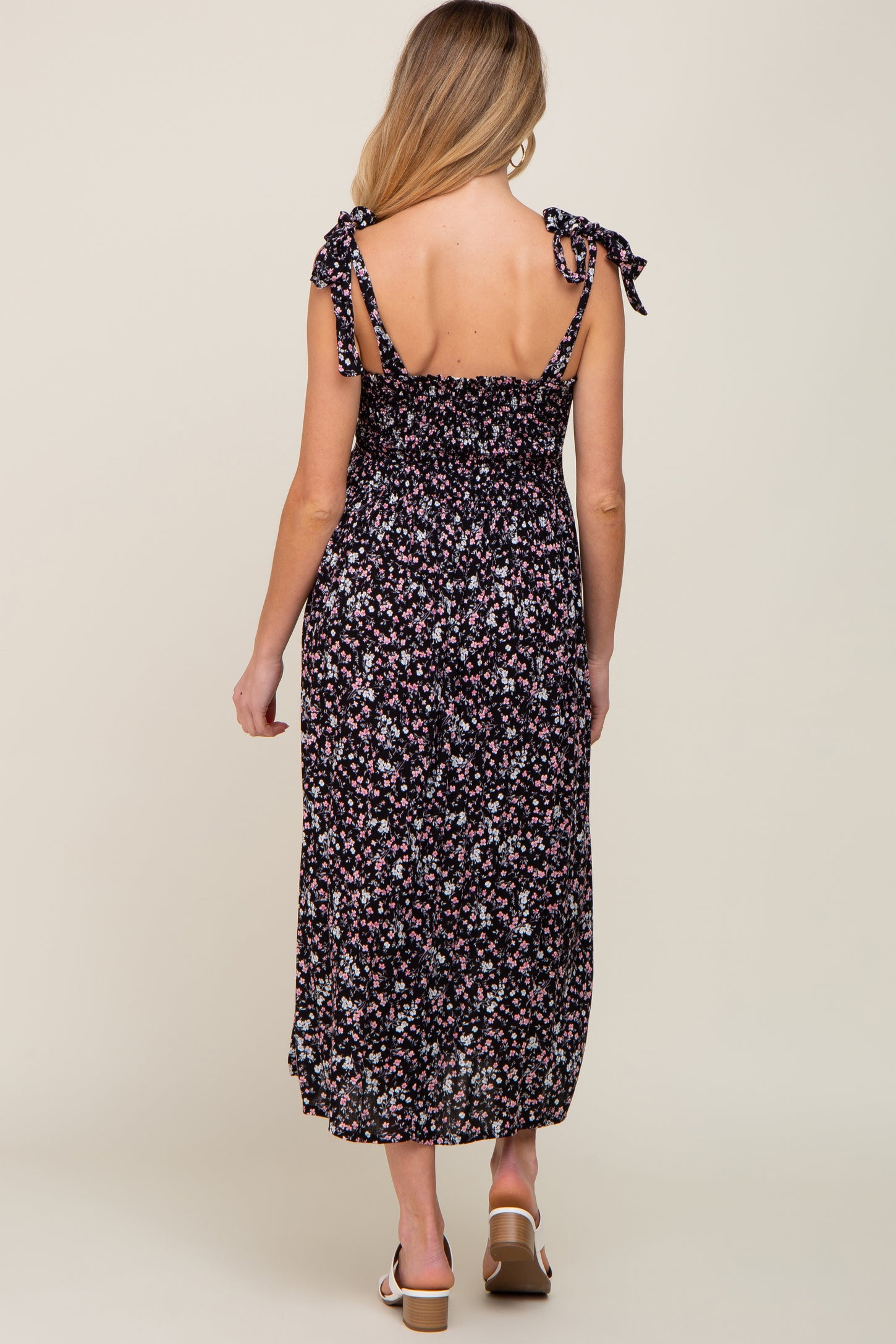 woman wearing a black floral maternity maxi dress with tie straps and smocked back, showing her baby bump
