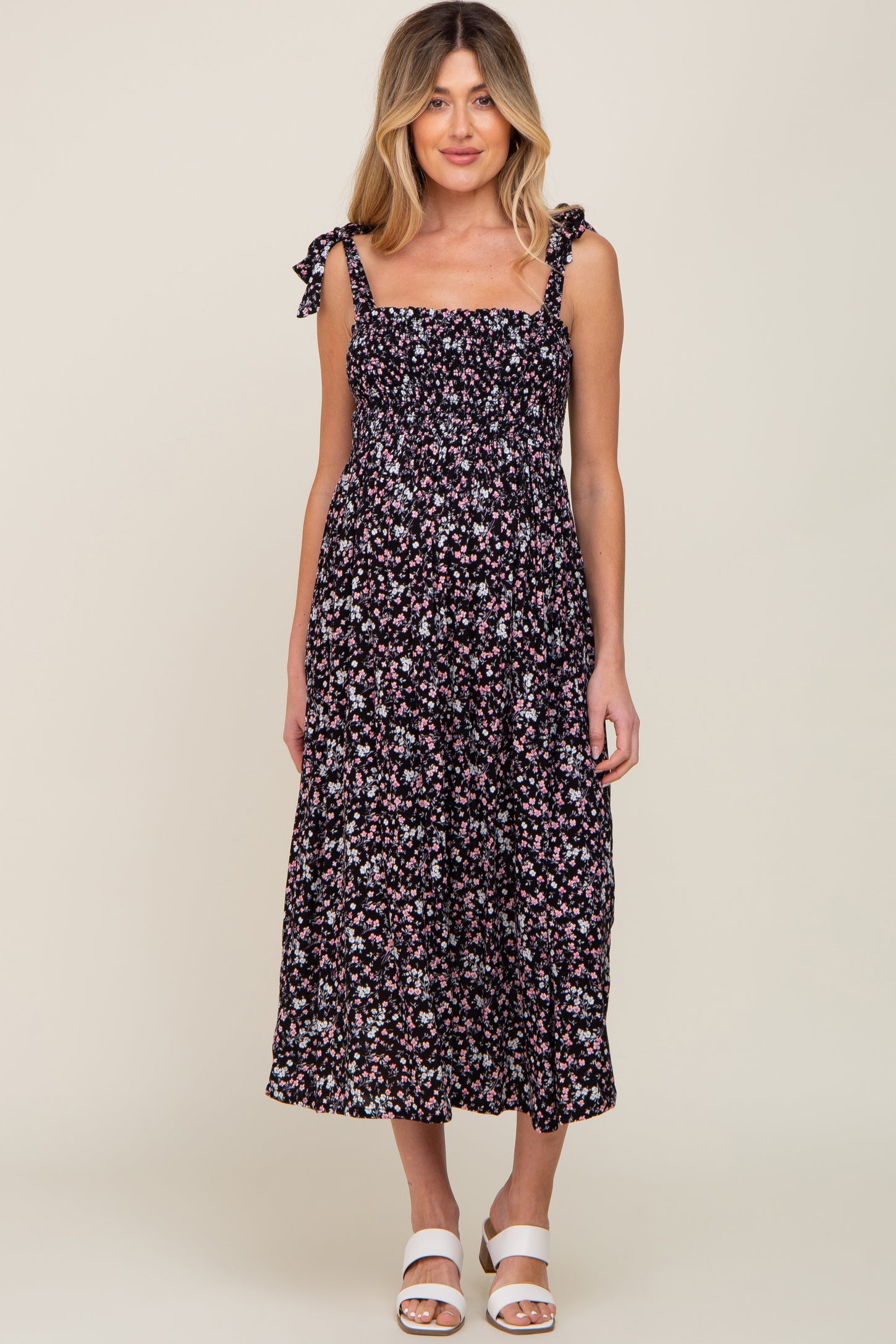woman wearing a black floral print maternity dress with adjustable tie straps and a flowy silhouette
