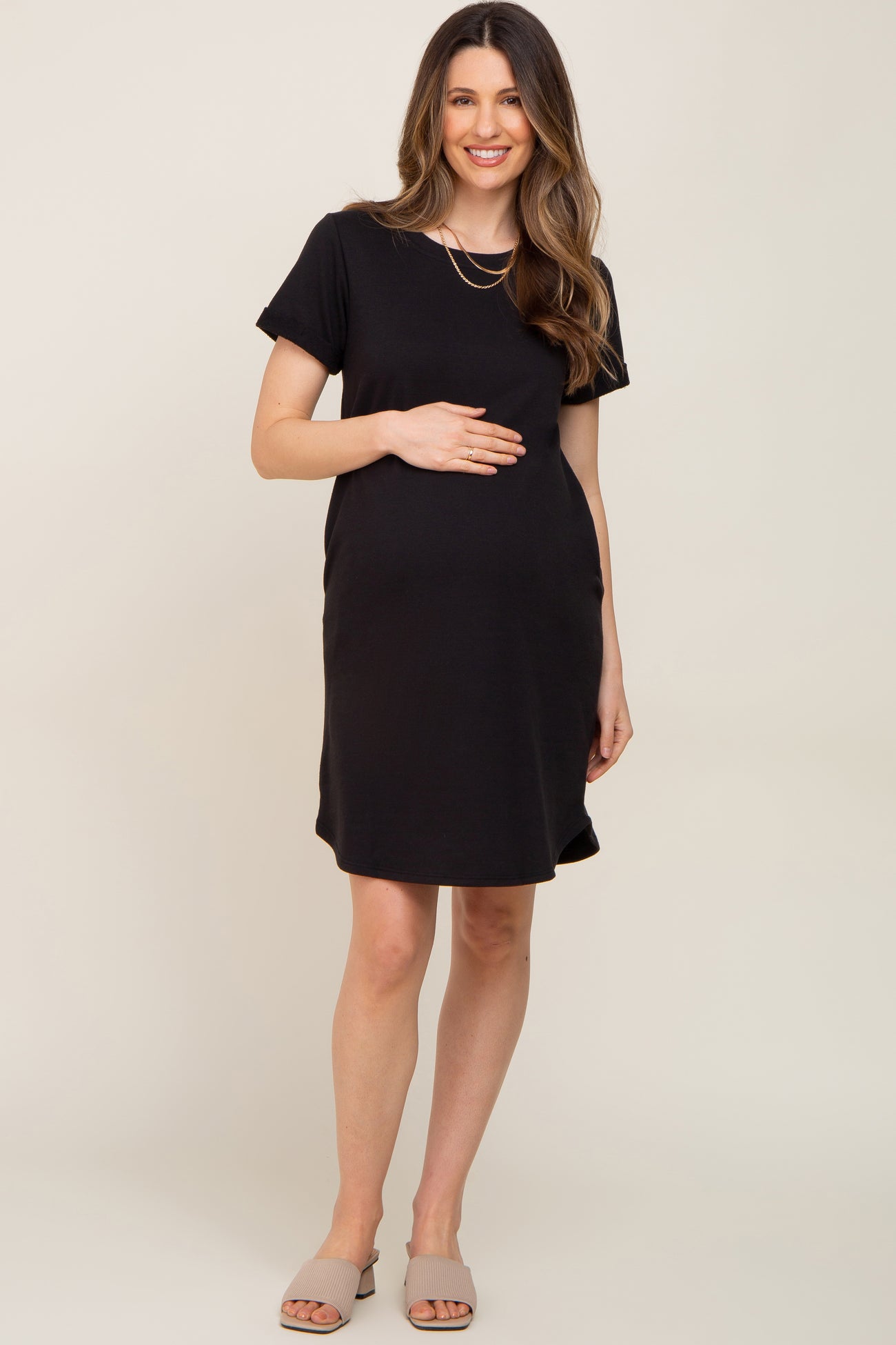 woman wearing a black short sleeve maternity dress and holding her baby bump