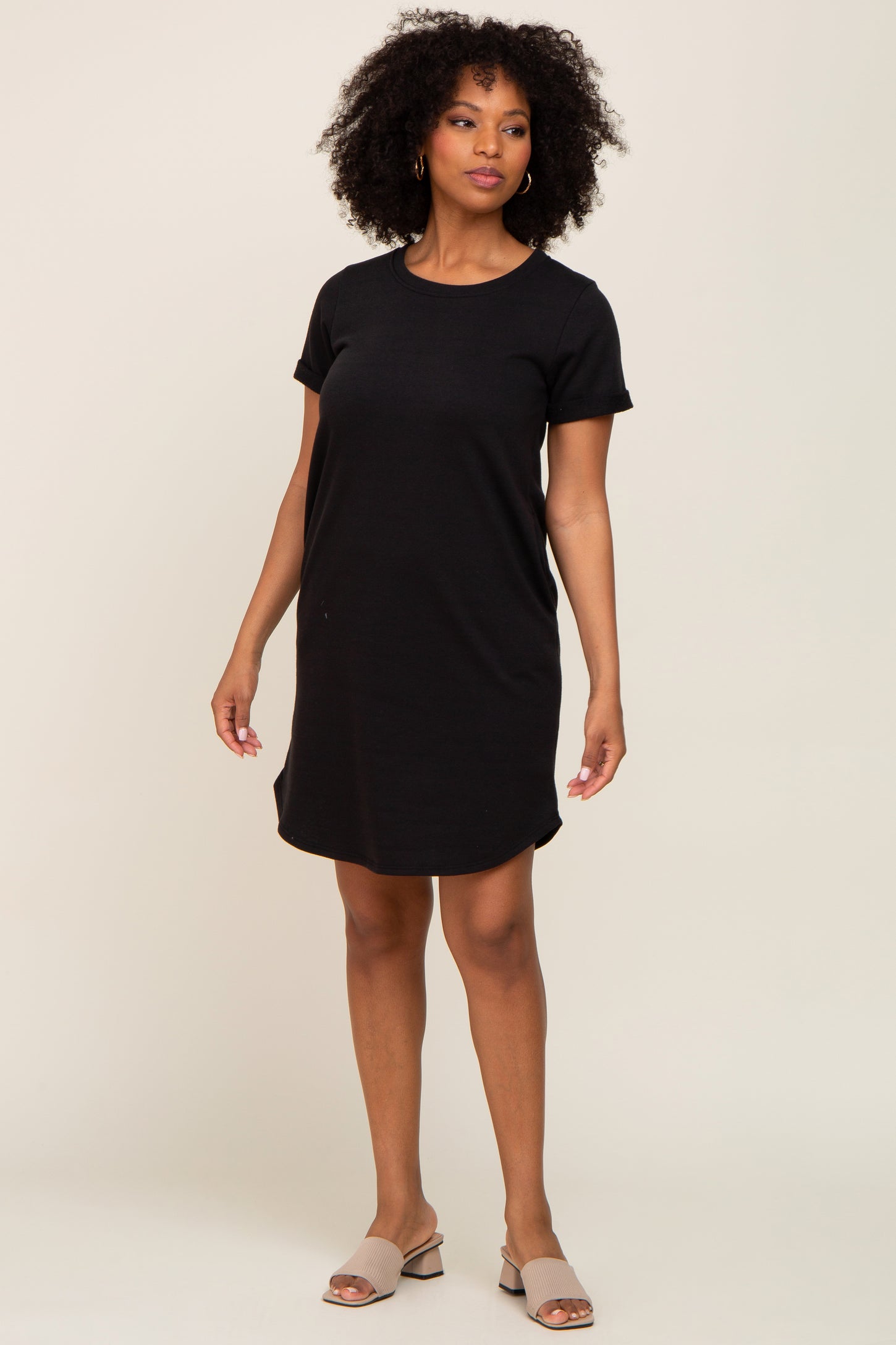 woman wearing a black short sleeve dress styled as a relaxed fit, standing on a plain background