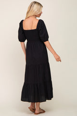 woman wearing a black tiered maxi dress with puff sleeves and a smocked bodice, shown from the back