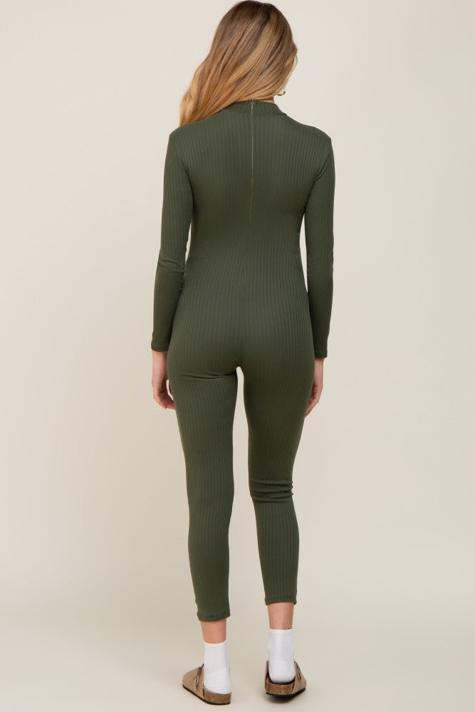 Back view of a woman wearing a long sleeve olive green ribbed jumpsuit with white socks and sandals