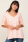 woman wearing a light peach v-neck t-shirt with a front pocket and blue jeans