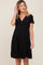woman wearing a black pleated maternity dress with short sleeves and a v-neckline, highlighting her baby bump