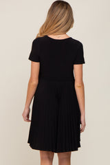woman wearing a black short sleeve maternity dress with a pleated skirt seen from the back