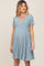 woman wearing a light blue short sleeve maternity pleated dress and showing her baby bump