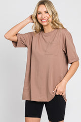 Woman wearing a mauve oversized pocket t-shirt and black biker shorts against a white background