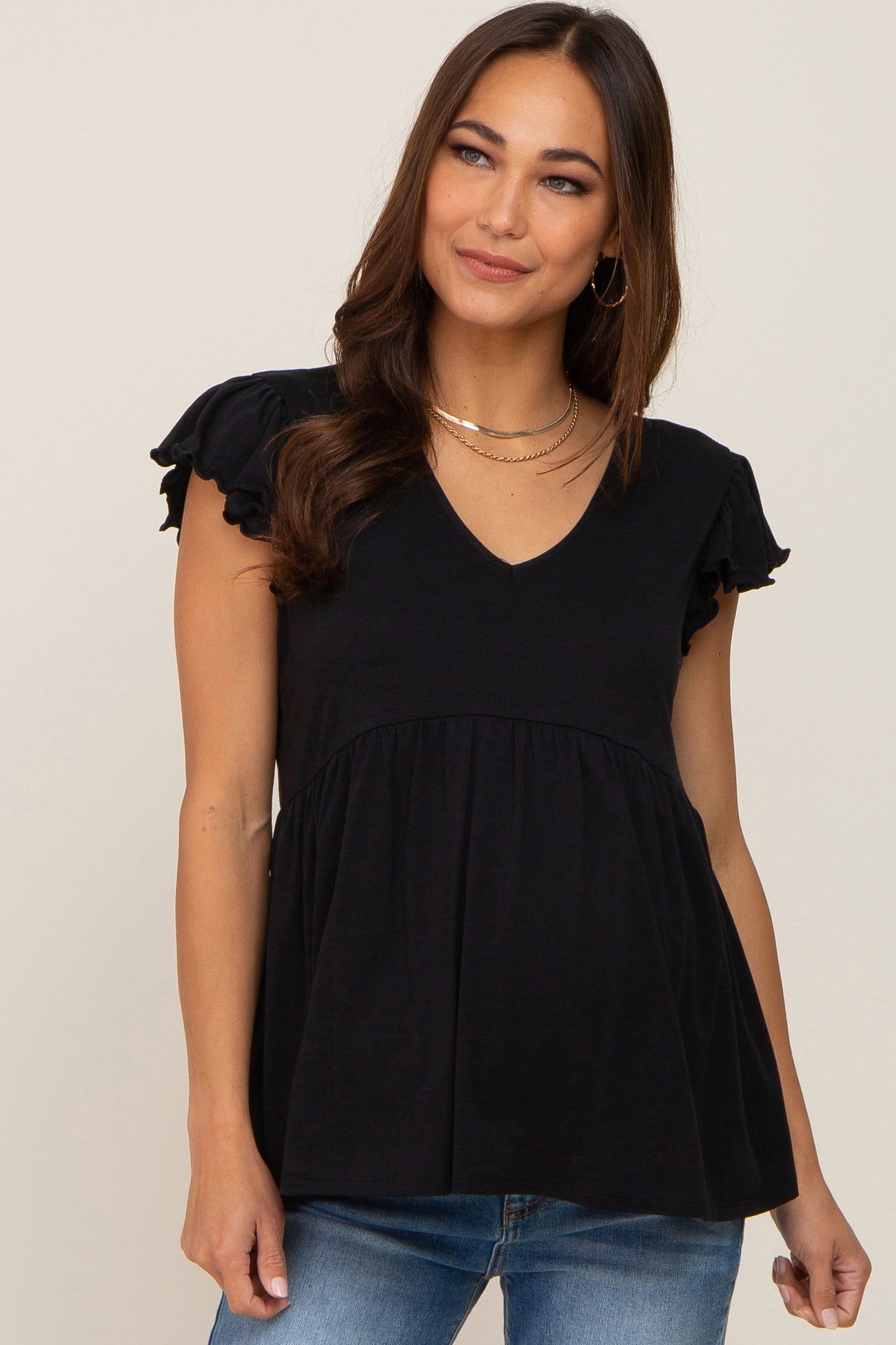 woman wearing a black v-neck maternity top with ruffle sleeves and blue jeans
