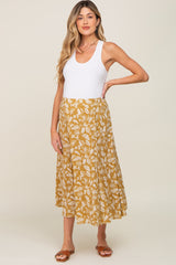 woman wearing a white tank top and a mustard yellow floral midi skirt with brown sandals