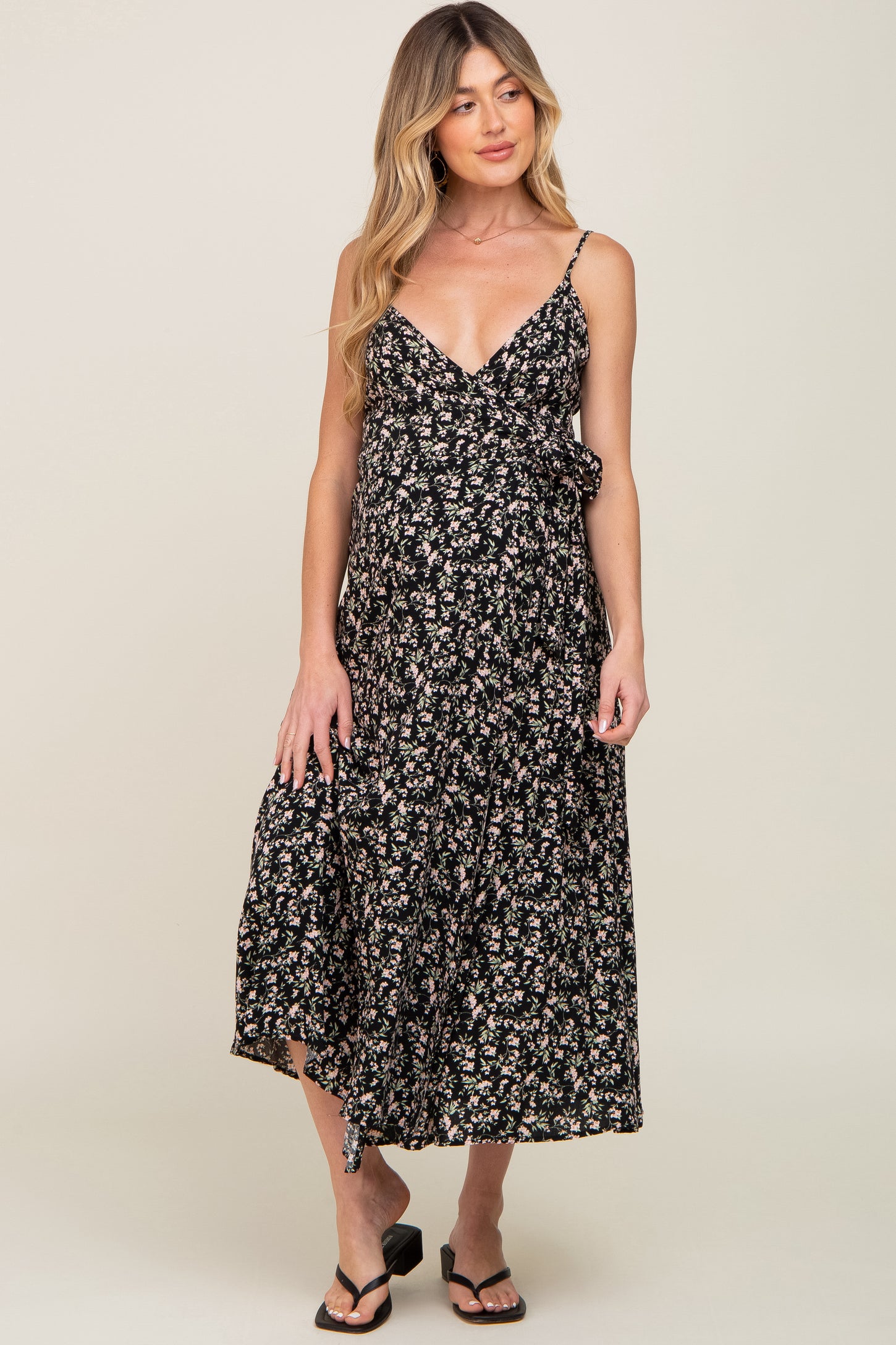 woman wearing a black floral maternity wrap midi dress with spaghetti straps and sandals