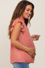 smiling pregnant woman wearing a rose pink ruffle sleeve maternity top and blue jeans