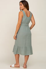 woman wearing a sage green maternity dress with ruffle straps and a tiered hem, showing a baby bump from the back