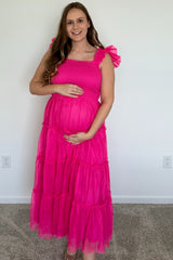 Pregnant woman in a bright pink smocked maternity dress with ruffled sleeves and a tiered tulle skirt