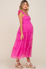 woman wearing a bright pink tiered tulle maternity dress with ruffle straps and a visible baby bump