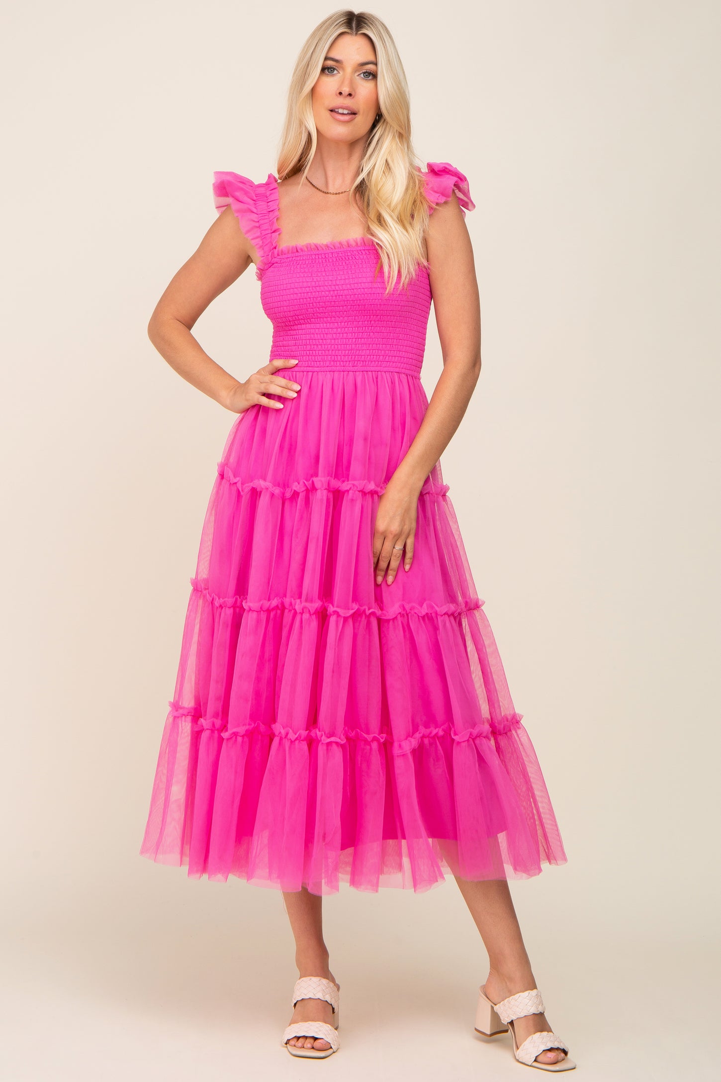 woman wearing a bright pink tiered tulle dress with ruffle sleeves and a square neckline