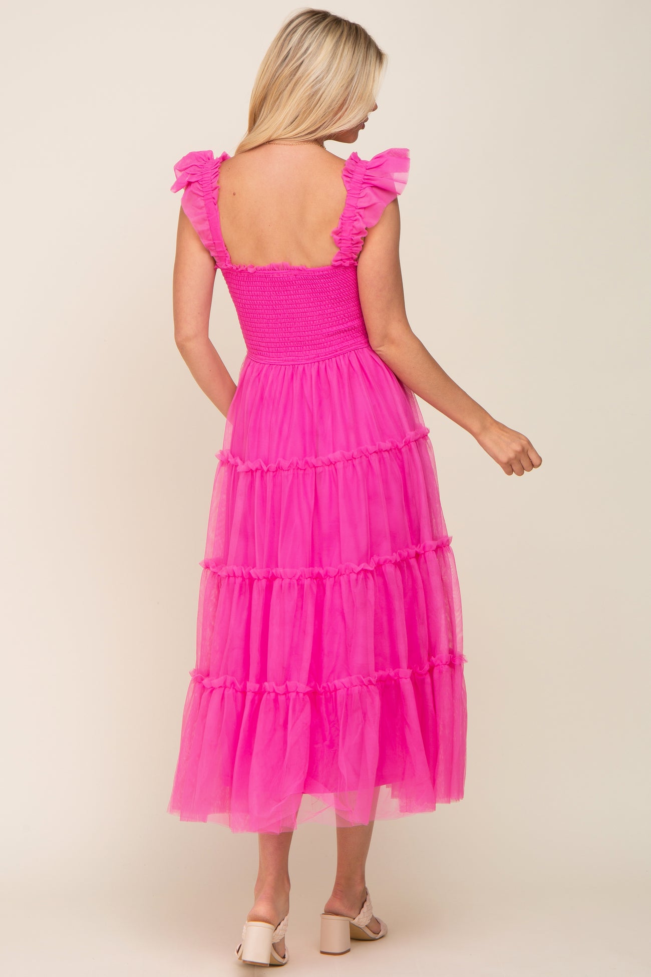 woman wearing a pink tiered maxi dress with ruffled straps and a smocked bodice