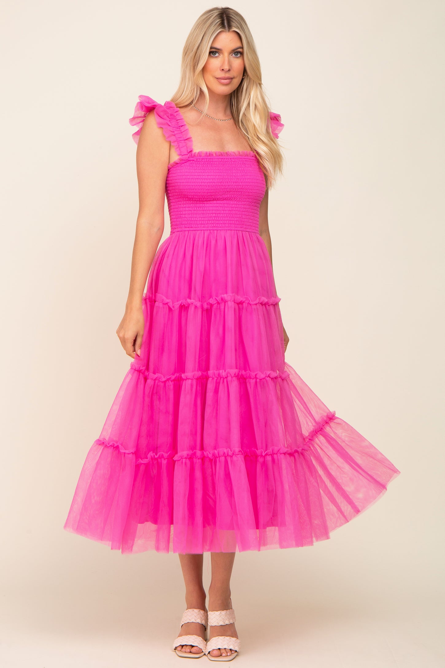 woman wearing a bright pink tiered maxi dress with ruffled straps and a smocked bodice