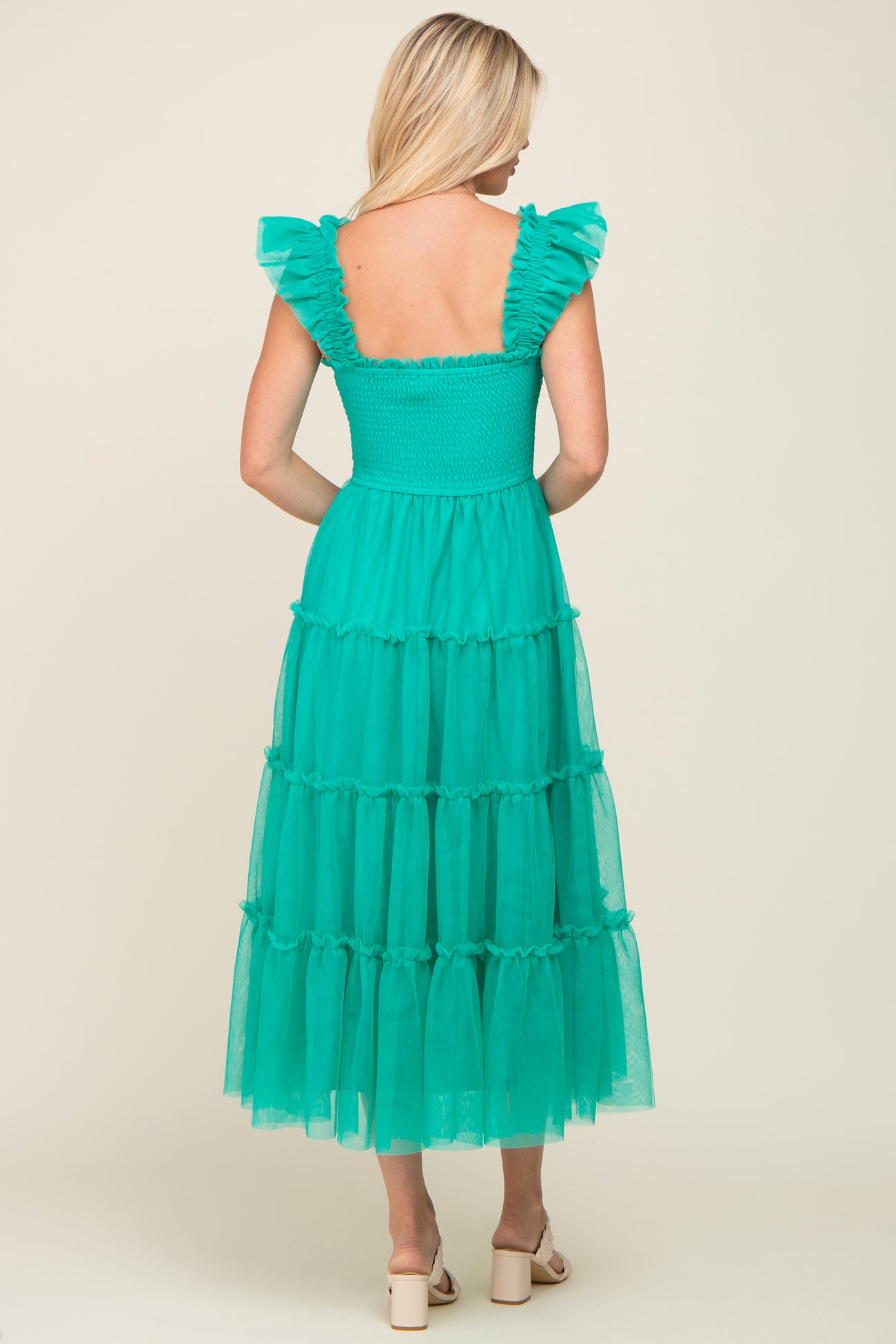woman wearing a back view of a teal tiered maxi dress with ruffle sleeves and a smocked bodice